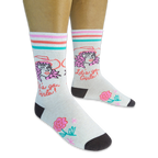 Person wearing cream socks with a pink-haired cowgirl, Let's go Girls text, retro stripes, and a pink rose on a black backdrop.