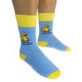 Person wearing light blue crew socks with yellow accents on a black background, showing the pixel rubber duck and text design.