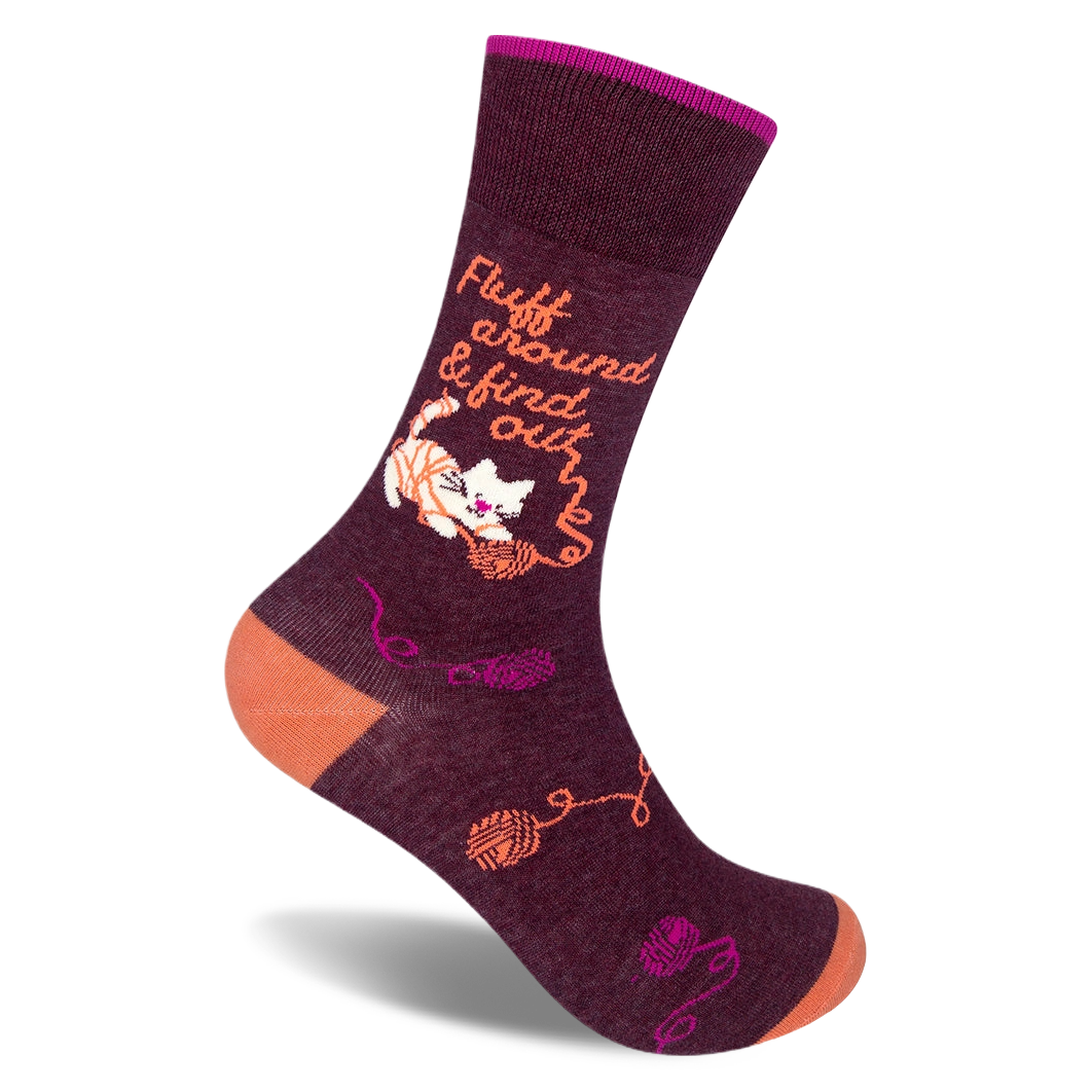 Dark burgundy crew sock with an orange heel and toe. Features a white cat tangled in yarn and text Fluff around & find out.