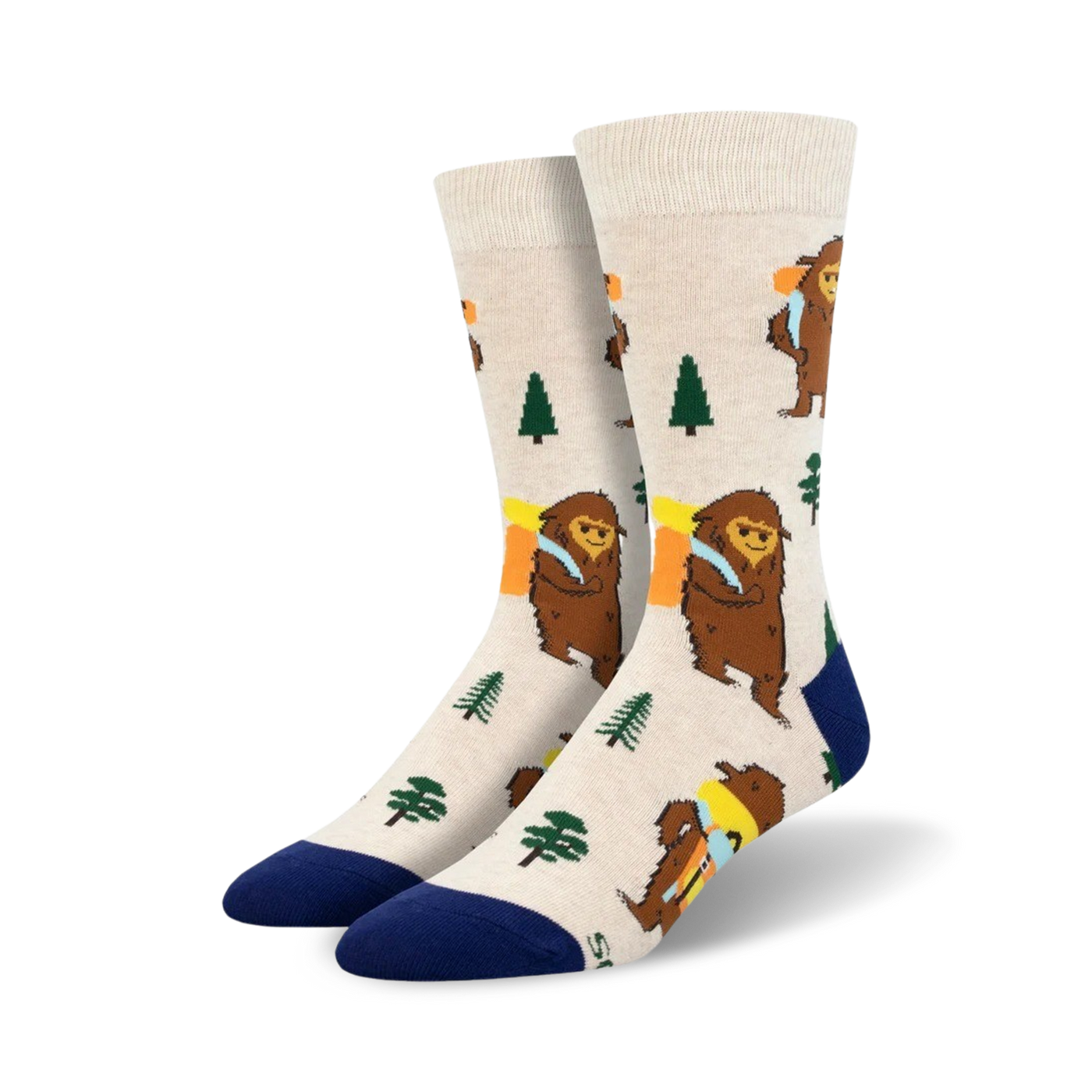 Cream-colored crew socks with a whimsical design of brown Bigfoot figures carrying backpacks, accented with green trees and a navy blue cuff.