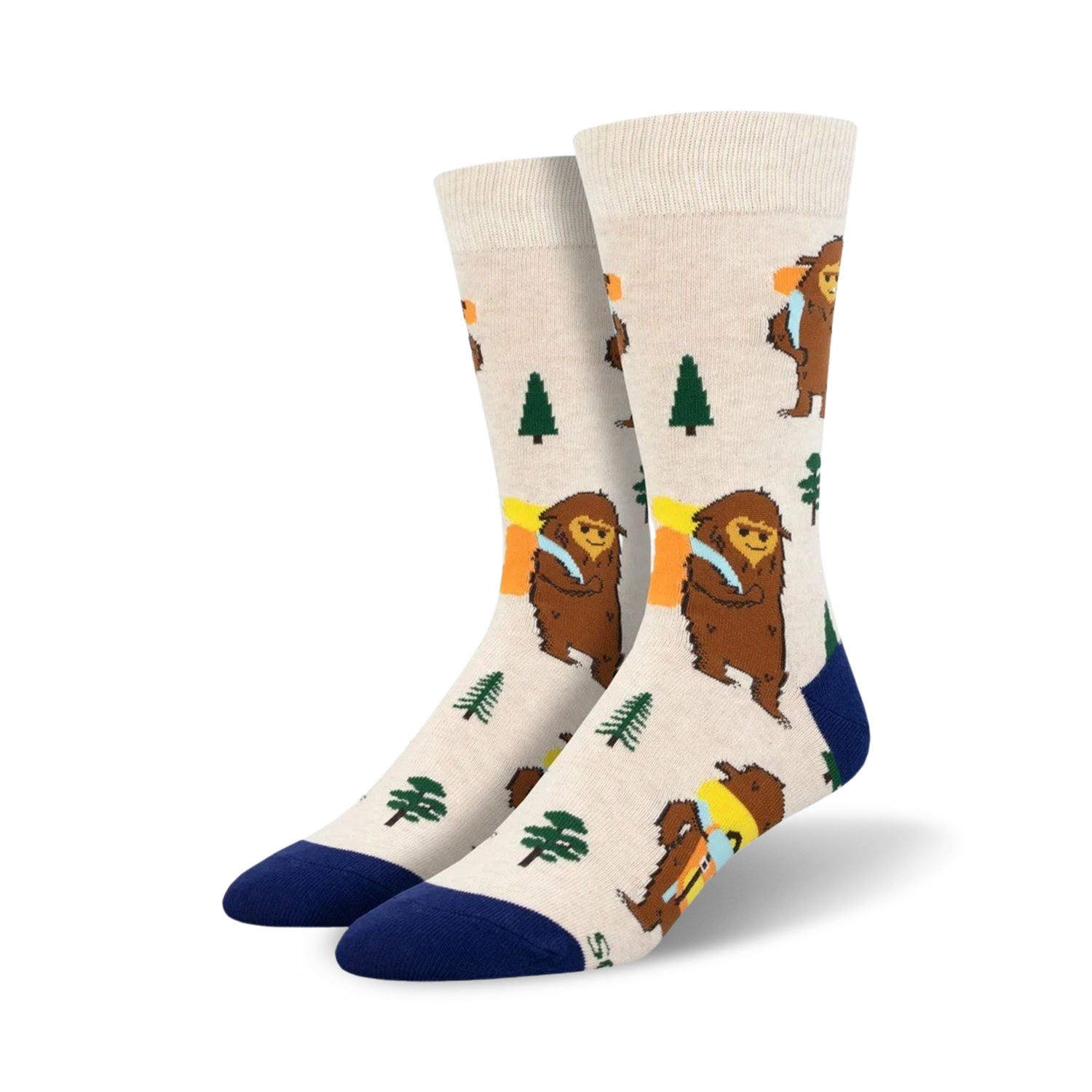 Cream-colored crew socks with a whimsical design of brown Bigfoot figures carrying backpacks, accented with green trees and a navy blue cuff.