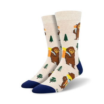 white crew socks featuring cartoon bigfoot hiking through green woods with brown trees. perfect for adventurers and bigfoot enthusiasts. men's size.