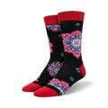 A pair of crew socks with a black background and colorful mandala designs in shades of purple, red, and teal. The socks have red cuffs.