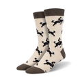 Pair of cream crew socks with a repeating pattern of black dogs riding horses. Brown cuff.
