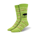 Pair of lime green crew socks. Design features pink pigs running along a white fence, with a black pig silhouette and 'Farm Boy' text.