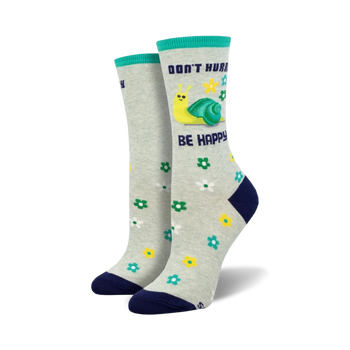 grey crew socks with blue toe, heel, and cuff feature a yellow-shelled snail, pink flowers, and green leaves. "don't hurry, be happy" is written on the cuff in blue.  