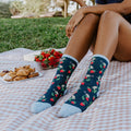 Lifestyle shot: Person wearing Berry Mice socks while enjoying a picnic outdoors. [lf]