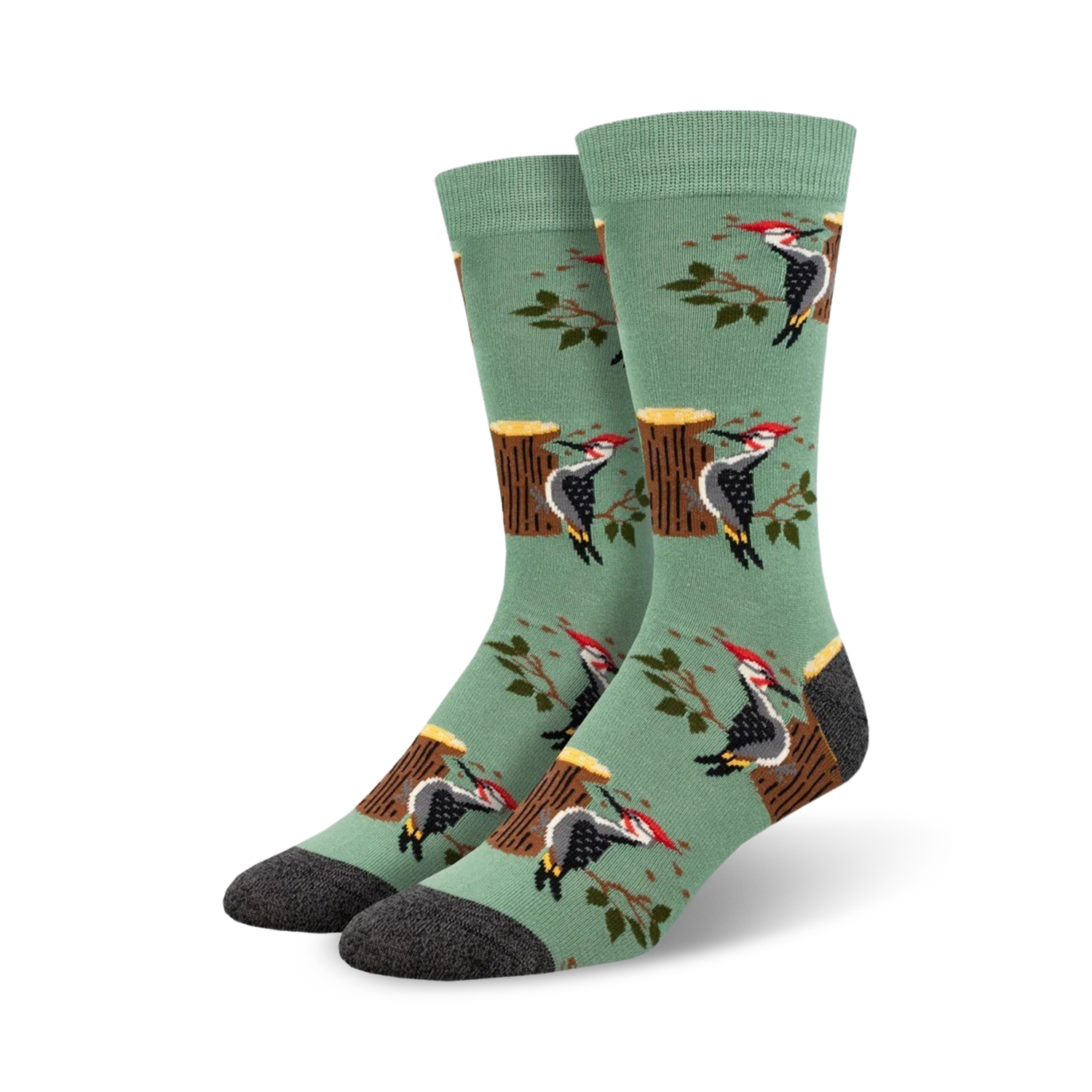 A pair of crew socks in sage green with a repeating pattern of woodpeckers on tree stumps and branches.