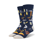 Pair of navy blue crew socks with a pattern of various tools, including hammers, saws, and measuring tools, in yellow and brown.