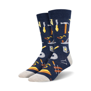 Pair of navy blue crew socks with a pattern of various tools, including hammers, saws, and measuring tools, in yellow and brown.