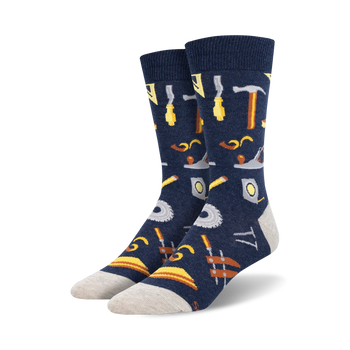 Pair of navy blue crew socks with a pattern of various tools, including hammers, saws, and measuring tools, in yellow and brown.
