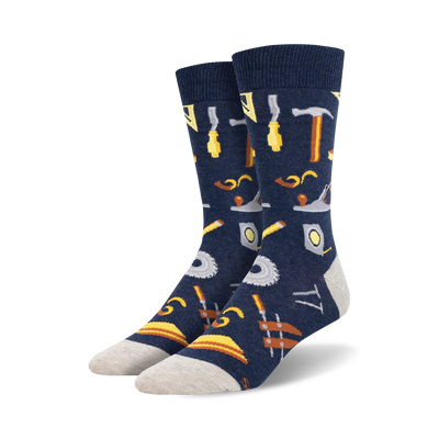 Pair of navy blue crew socks with a pattern of various tools, including hammers, saws, and measuring tools, in yellow and brown.