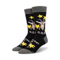 A pair of black crew socks with a goat design, gold stars, and 'G.O.A.T.' text.  The socks have a grey cuff.