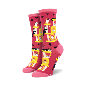pink crew length socks with a pattern of sleeping black cats on a yellow cat tree with paw prints in the background.  