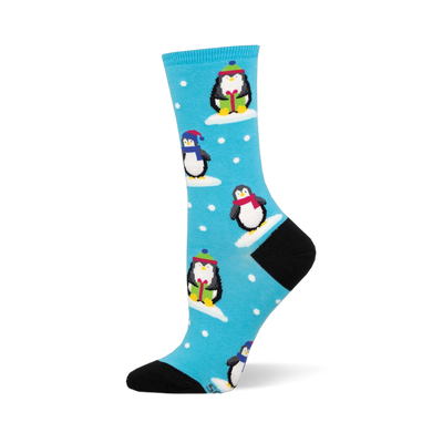 Bright blue sock with cute winter penguins wearing colorful hats & scarves, standing on snow patches with white snowflakes. B