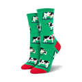 Pair of women's crew socks. Green background with a repeating pattern of black and white cows wearing Christmas hats and scarves.