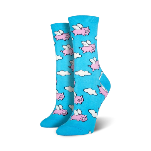 Pair of women's crew socks in light blue. The socks feature a whimsical pattern of pink pigs with wings flying amidst white clouds.