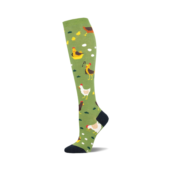 the chicken ranch socks are an amusing pair of socks that feature a pattern of chickens, chicks, eggs, and grassy patches on an olive green background. socks that are knee-high and have a black heel and toe. }}