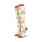 Pair of knee-high cream socks with repeating orange, blue, and purple rainbow heart patterns. Terracotta cuffs, heels, and toes.