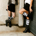 Lifestyle shot: Two women wearing black and white musical note socks. [lf]