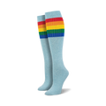 Pair of light blue knee-high socks with a vibrant rainbow striped cuff against a white background.