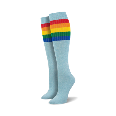 Pair of light blue knee-high socks with a vibrant rainbow striped cuff against a white background.