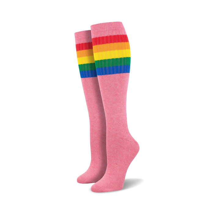 Pair of pink knee-high socks with a vibrant rainbow striped cuff against a white background.
