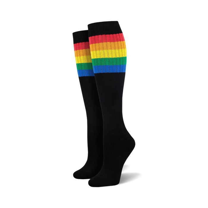 Pair of black knee-high socks with a vibrant rainbow striped cuff against a white background.