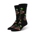 A pair of black crew socks with a repeating pattern of brown sloths hanging from green leaves. 