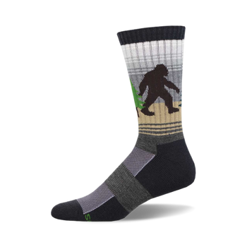 socks that are black, gray, and light brown with a pattern of sasquatches in the woods. the sasquatches are black and brown and are carrying green trees. socks with a ribbed top and a cushioned foot.