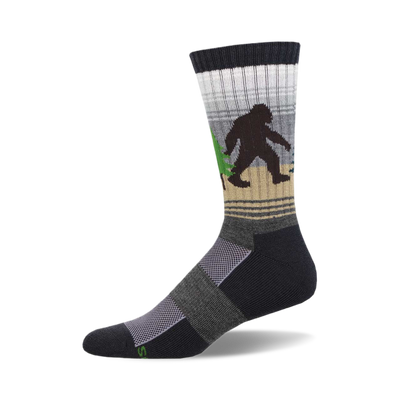 socks that are black, gray, and light brown with a pattern of sasquatches in the woods. the sasquatches are black and brown and are carrying green trees. socks with a ribbed top and a cushioned foot.