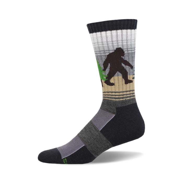socks that are black, gray, and light brown with a pattern of sasquatches in the woods. the sasquatches are black and brown and are carrying green trees. socks with a ribbed top and a cushioned foot. }}