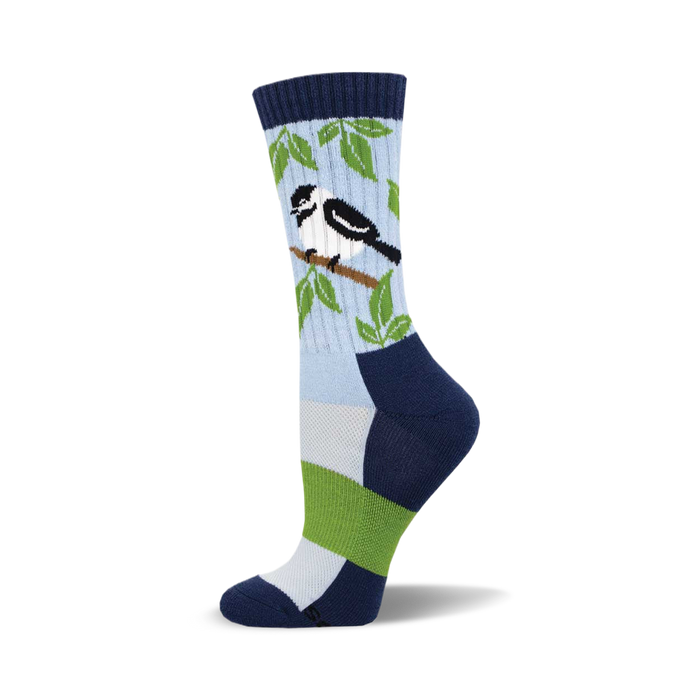 the blue sock has a pattern of green leaves and small black and white birds with a yellow or gold beak. the top of the sock is navy blue with a lighter blue toe and heel. }}