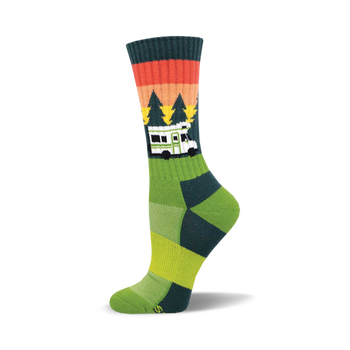 the green sock has a pattern of orange, red, and brown stripes near the top. below that are green pine trees of different heights. there is a white camper van with black windows and the word "home" on the front in black text. the bottom of the sock is yellow with two thin green stripes above the yellow.
