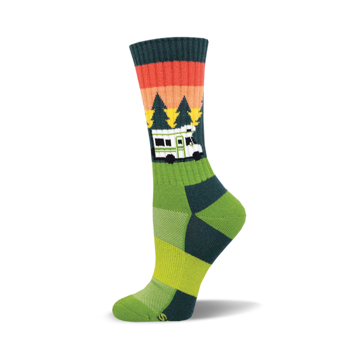 the green sock has a pattern of orange, red, and brown stripes near the top. below that are green pine trees of different heights. there is a white camper van with black windows and the word 