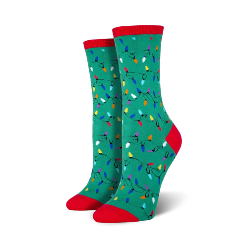 Lifestyle shot of a person wearing red Christmas Lights socks, sitting near a Christmas tree.