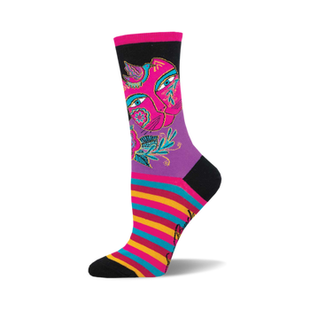 socks that are black, purple, pink, blue, yellow and red. they have a pattern of a cat's face with flowers and birds on it. the cat's face is split in half with one half being a lighter shade of pink than the other half. the eyes are blue and the nose is black. the flowers are pink, yellow, and blue. the leaves are green. the birds are blue and yellow. the socks also have a striped pattern of pink, blue, yellow and red at the end of the sock by the toes.