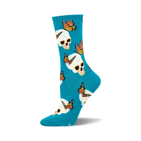 the blue socks have an all-over pattern of white skulls with pink, yellow, and orange flowers on them. there are also monarch butterflies in various positions around the skulls.