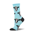 Crew socks featuring a light blue background and repeated pattern of black and white cows wearing flower crowns.