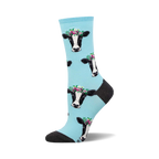Crew socks featuring a light blue background and repeated pattern of black and white cows wearing flower crowns.