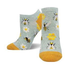 socks with a pattern of bees, beehives, and flowers on a blue background. the bees are black and yellow, the beehives are yellow and black, and the flowers are white with yellow centers.