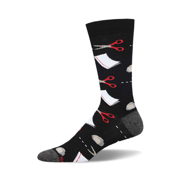 socks that are black and have a pattern of red scissors and grey rocks scattered all over. there is also a white square with a dotted line around it to represent paper. }}
