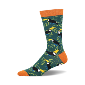 socks with a pattern of toucans, leaves, and bamboo. the toucans are black, yellow, and blue with orange feet and they are standing on branches of bamboo. the leaves are green with yellow and orange veins. the background is dark green.