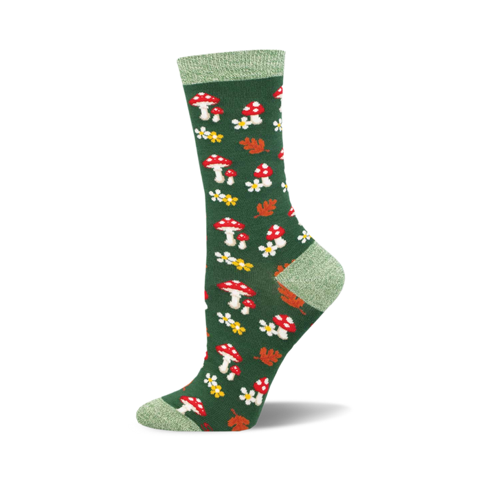 the sock is green with an all over pattern of red and white mushrooms, yellow flowers with white centers, and orange and red leaves. the top of the sock is solid green.