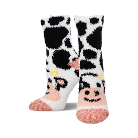 a pair of fuzzy socks with a black and white cow print.  the toes of the socks are pink.