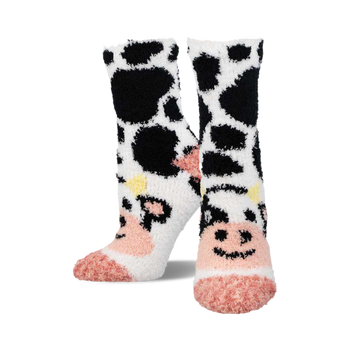 a pair of fuzzy socks with a black and white cow print.  the toes of the socks are pink.