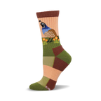 Close-up of a woman's crew sock. The sock features a colorful patchwork design in muted greens, browns, and peach, and an illustration of a quail among poppies.