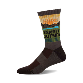 a gray sock with a design on it that says "take it outside". the design includes a setting sun, a blue lake, and some mountains.