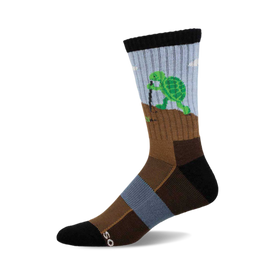 a sock with a green turtle digging a hole in the ground with a stick. the sock is blue and brown.