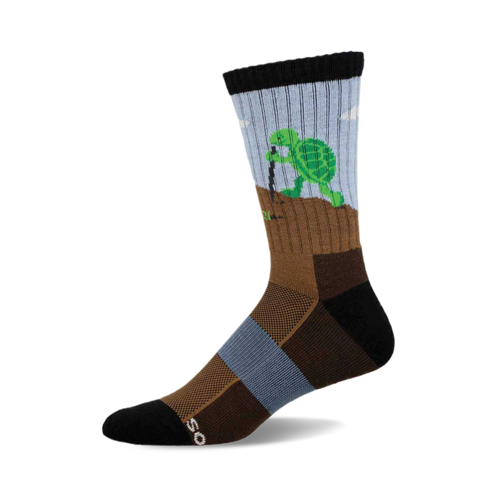 a sock with a green turtle digging a hole in the ground with a stick. the sock is blue and brown. }}